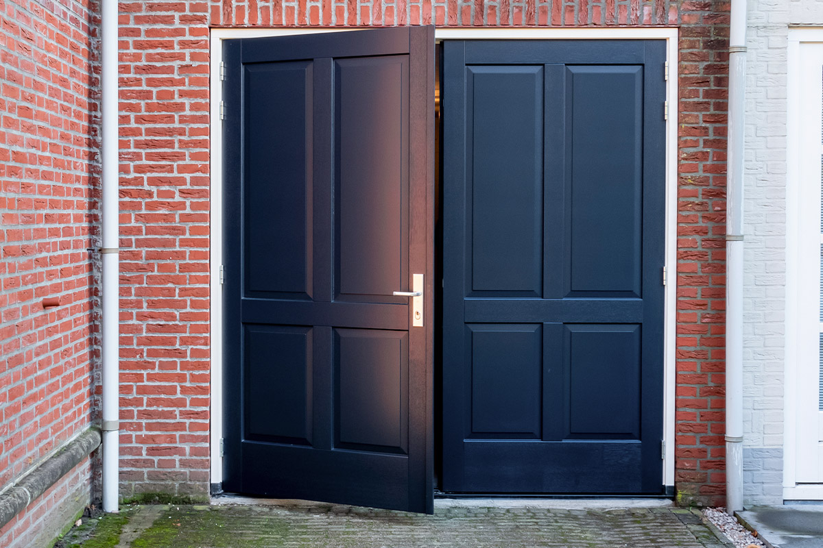 openslaande-garagedeur-bossing Hardhouten openslaande garagedeur met sierlijsten